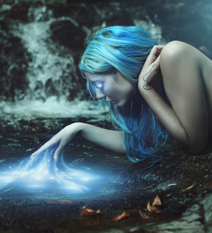 A fae woman before a glowing pool.