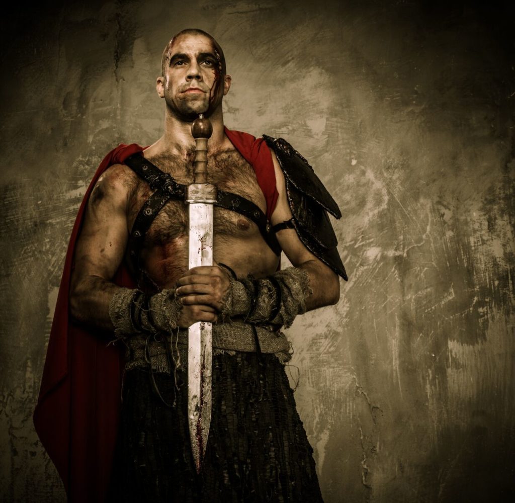 A warrior holding a blade stands proudly against a plain background.