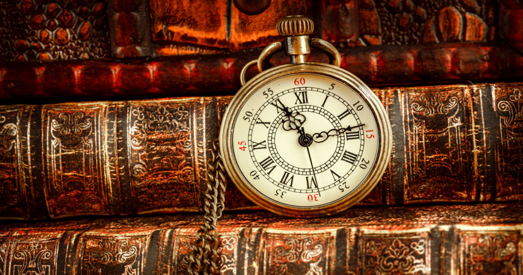 A picture of a pocketwatch on several old hardback books.