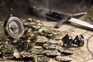 A pile of gold coins sits upon a table surrounded by trinkets.