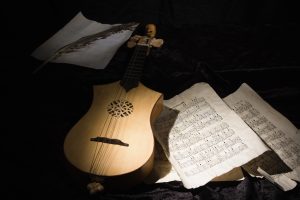 A mandolin lies among scattered music sheets in a half light