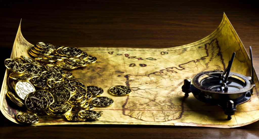 A treasure map and coins sit upon a wooden table