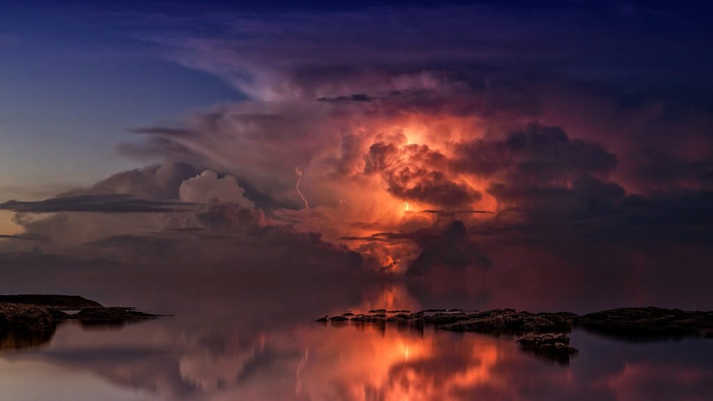 Thunderstorm over the sea, orange lightning lighting up its heart