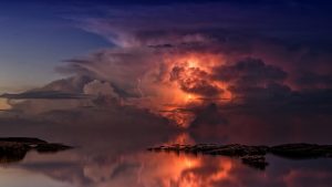 Thunderstorm over the sea, orange lightning lighting up its heart