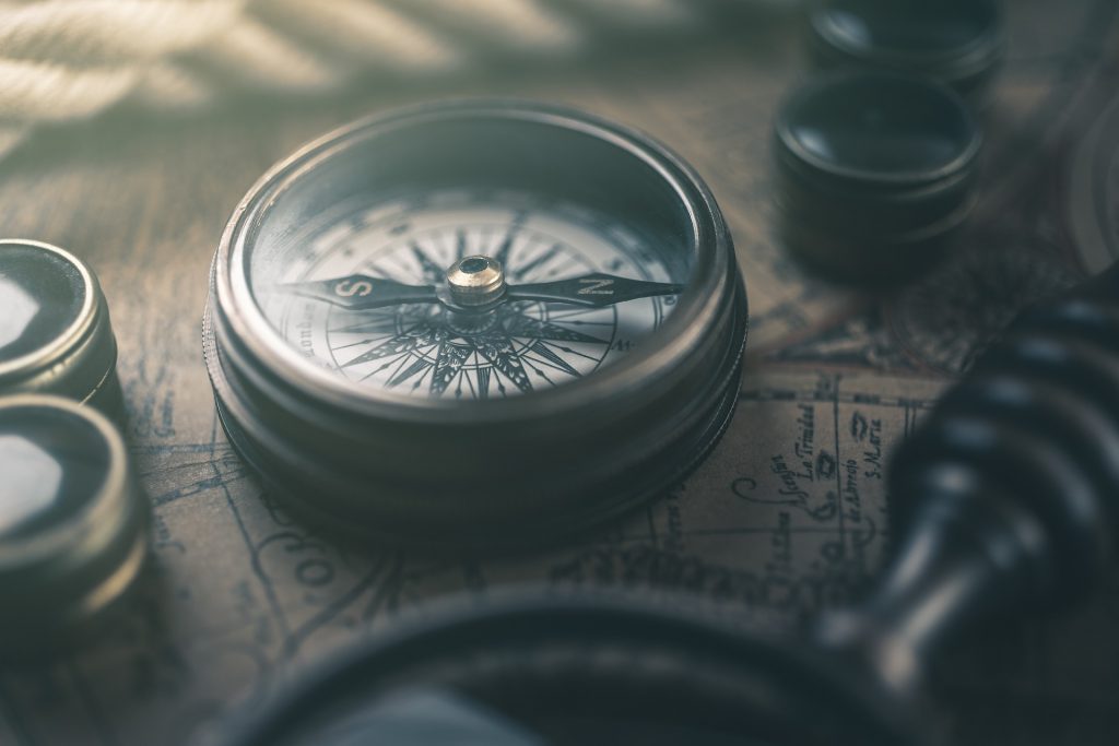 A compass lies upon a table with maps