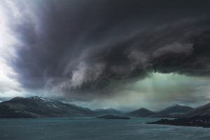 A dark storm gathers over a body of water