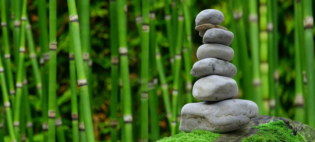 A peaceful zen garden with bamboo and stones in a pile.