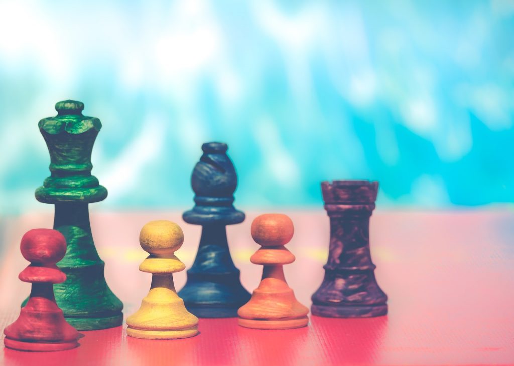Colourful chess pieces stand on a flat surface