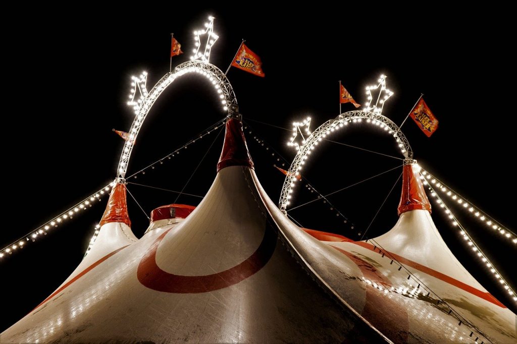 The outside of a circus tent illuminated at night.