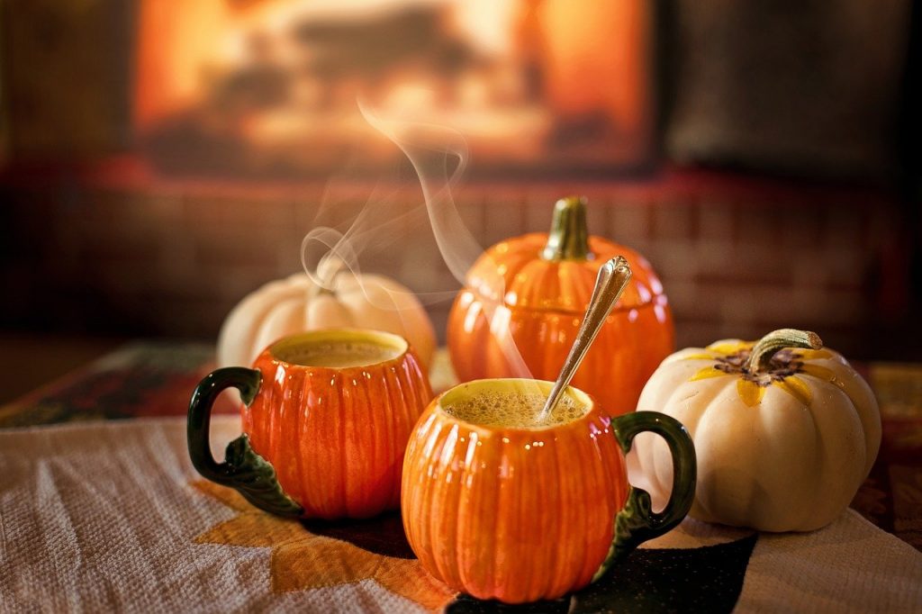 Pumpkin-shaped mugs steaming with lattes
