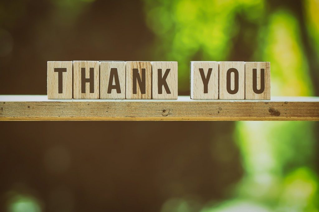 A wodden shelf against a green background, letters on the shelf spell out "Thank You"