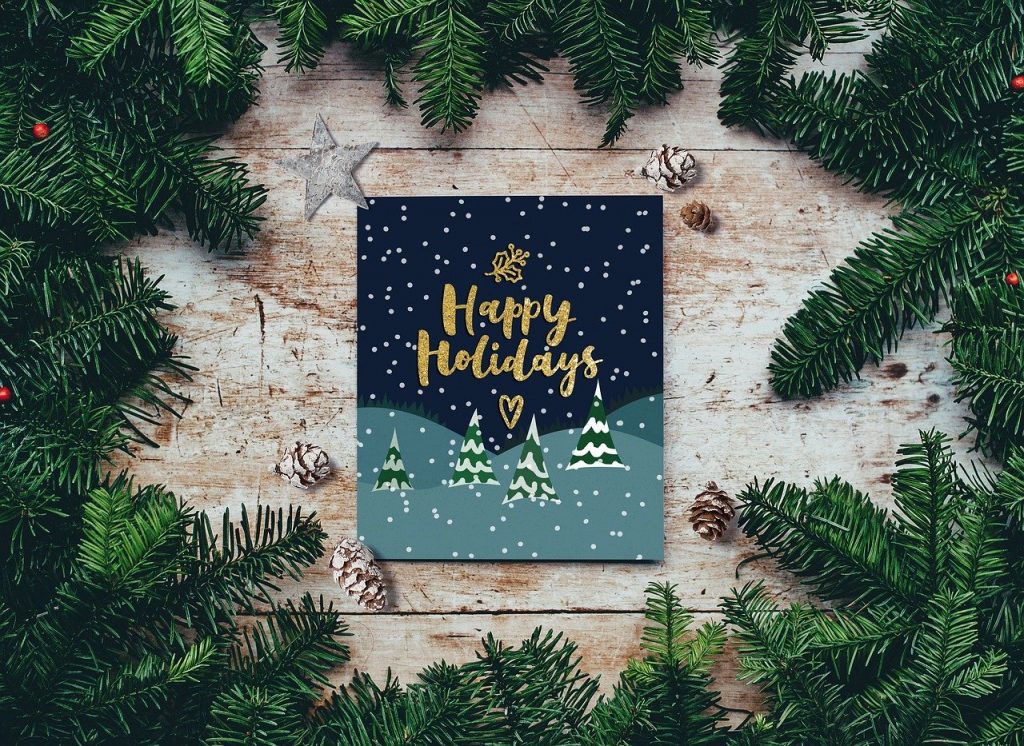 A holiday card with Happy Holidays written upon it, surrounded by firs