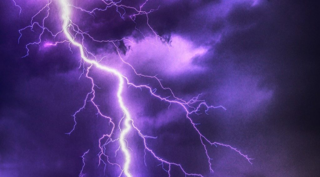Lightning splits purple, stormy skies.