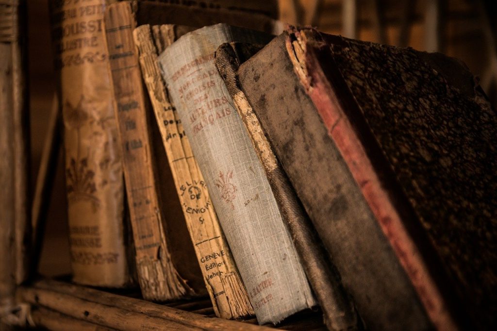 A collection of very old books sits on a shelf.