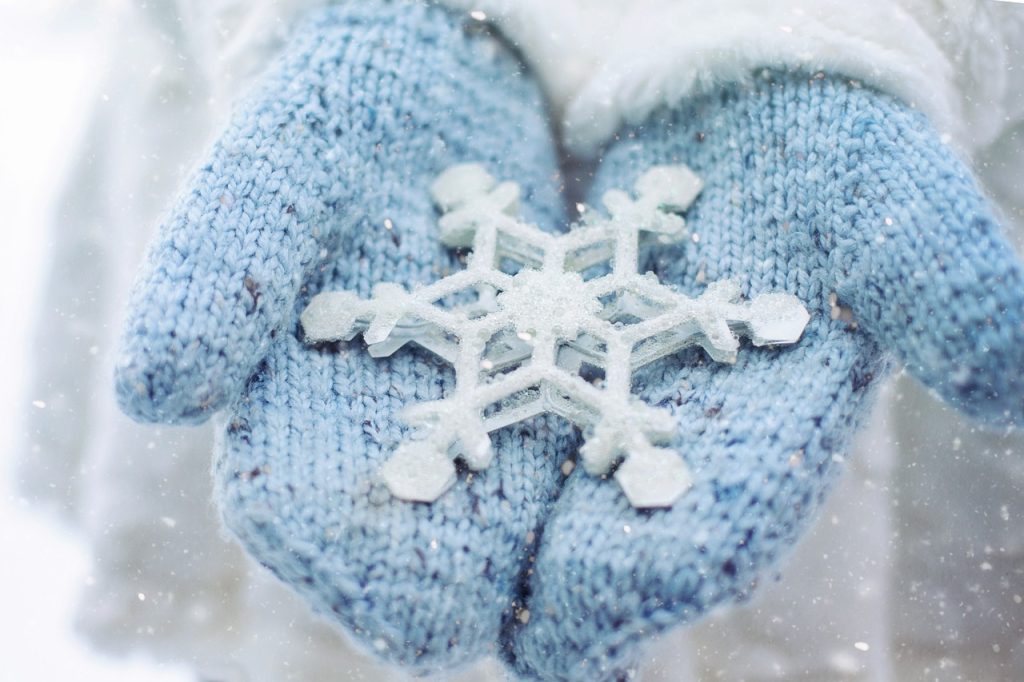 Knit baby blue mittens hold a perfect snowflake in the front.