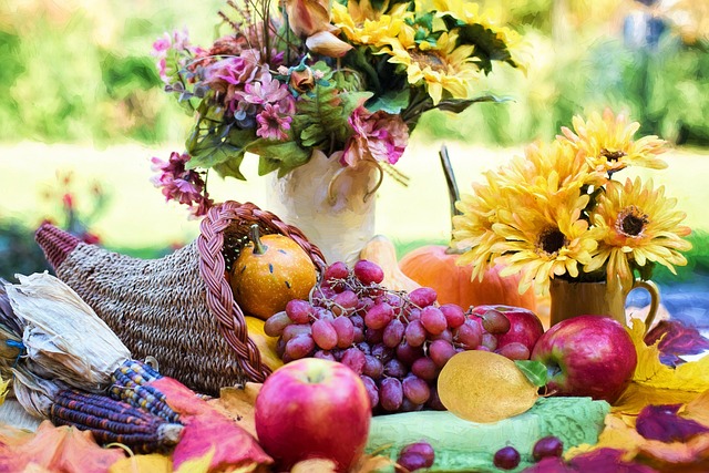 A cornucopia sits upon an outdoor table, surrounded by flowers.