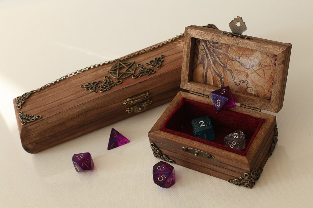 A handful of coloured dice sitting in a box.