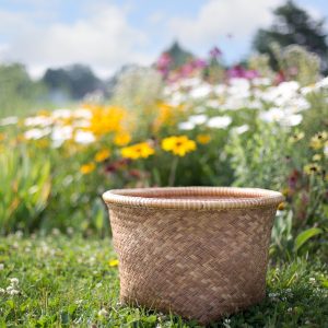 An empty basket against a background of a meadow with wildflowers.