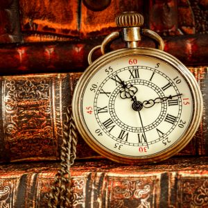 A picture of a pocketwatch on several old hardback books.