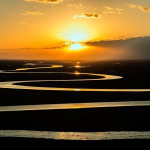 Sun rises over a meandering river.