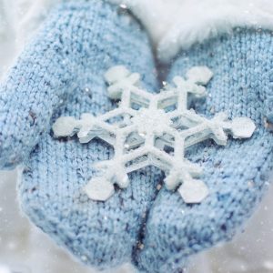 Knit baby blue mittens hold a perfect snowflake in the front.